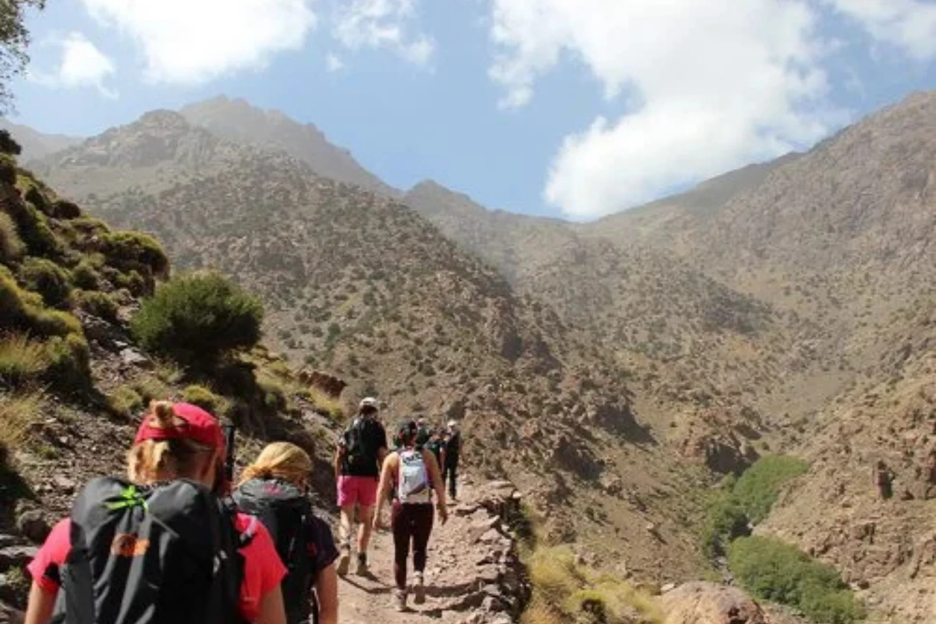 Group of hikers trekking along a rugged mountain trail in the Atlas Mountains, Morocco.