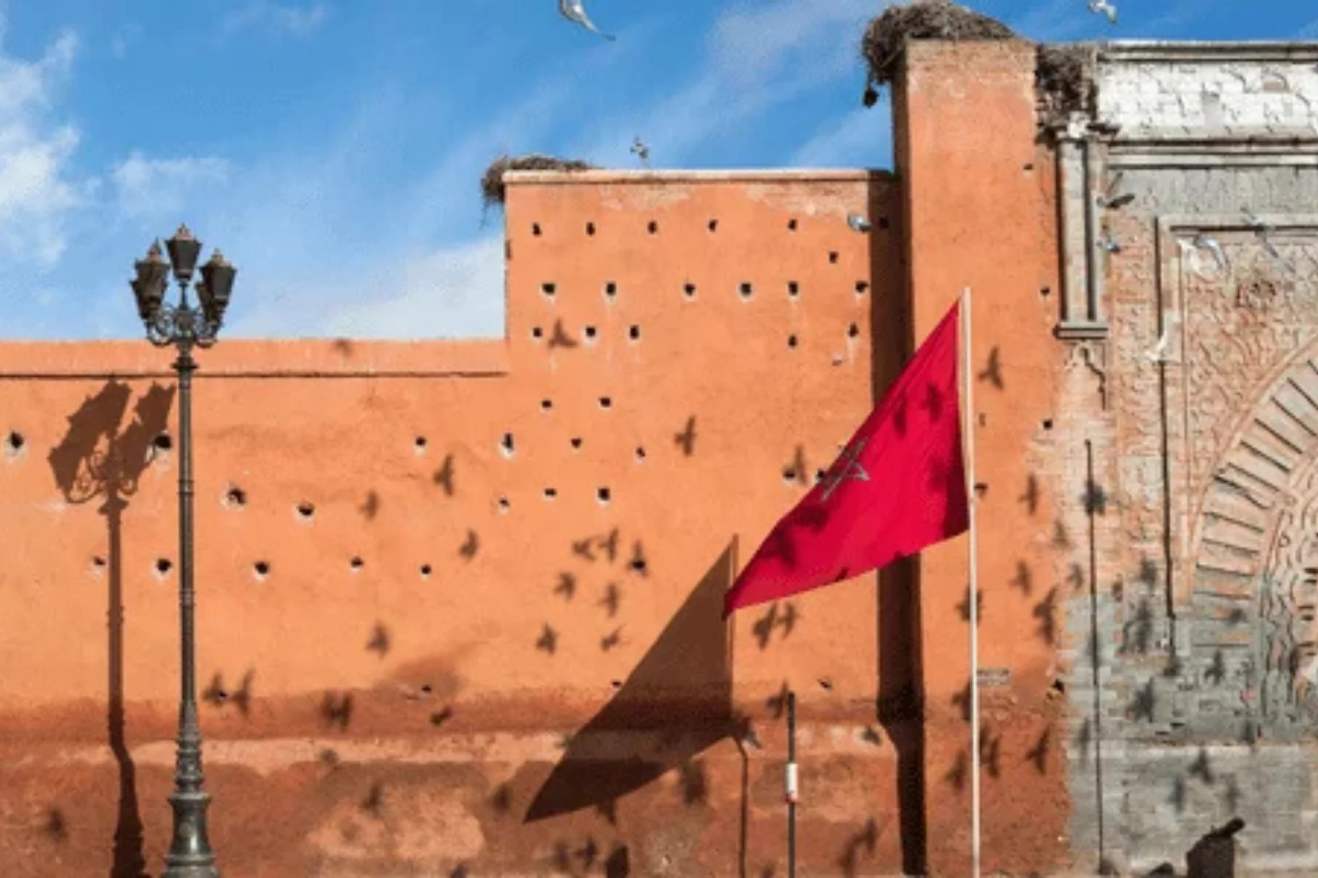 Red Moroccan flag flying in front of historical ramparts in Marrakech.