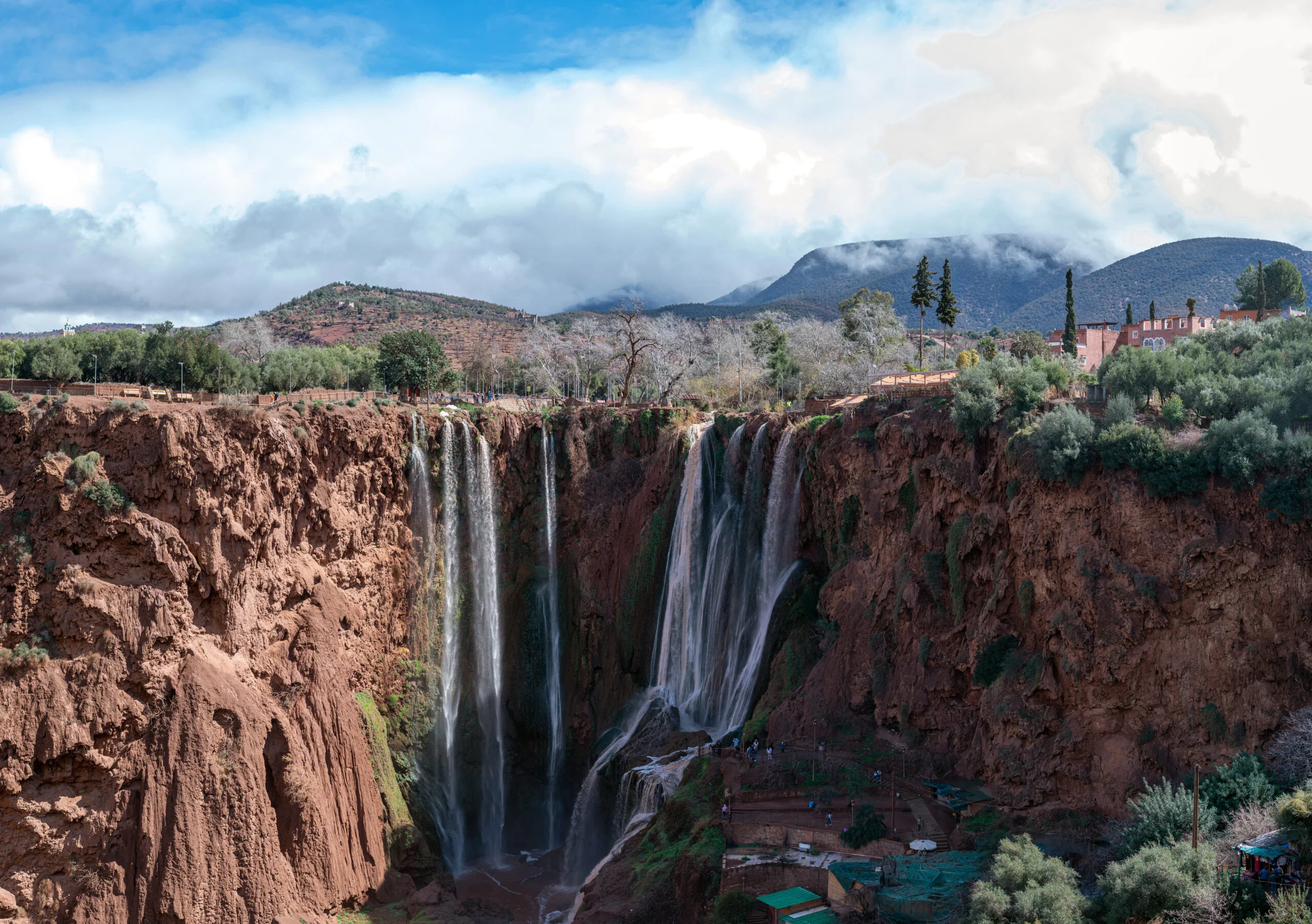 Ouzoud waterfalls cascade beautifully amidst rugged cliffs under a clear blue sky.